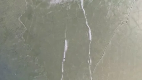 Aerial view of thin ice covering frozen lake surface with cracks. Stock Footage 337764648