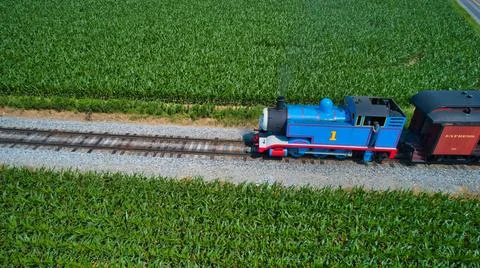 Aerial View of Thomas the Tank Engine Approaching Pulling Passenger Cars Blowing Stock Photos