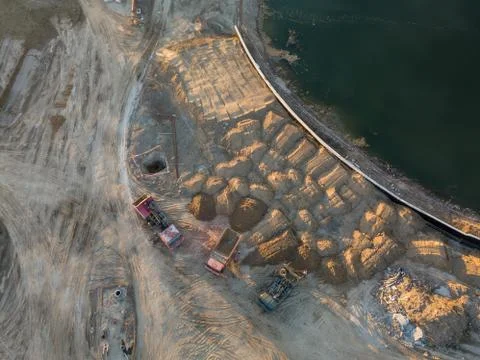 Aerial view of three multi-colored dump tip trucks unloading in a designated  Stock Photos