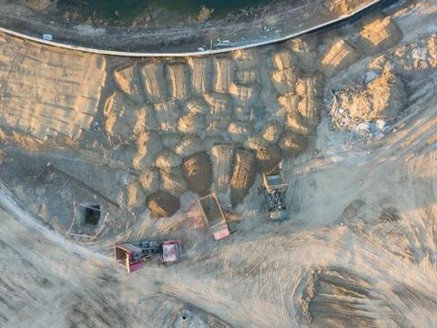 Aerial view of three multi-colored dump tip trucks unloading in a designated  Stock Photos
