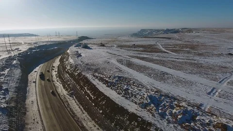 Aerial view of three suvs moving along the highway in the desert in winter Vídeo Stock 80243260