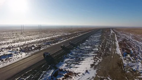 Aerial view of three suvs moving along the highway in the snow-coversd sandy Stock Footage 80984617