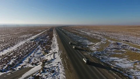 Aerial view of three suvs moving along the highway in the snow-coversd sandy Stock Footage 80984920