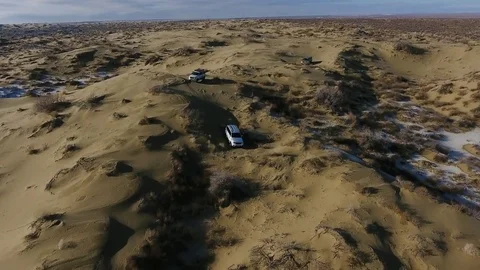Aerial view of three suvs moving through the snow-covered desert in winter Stock Footage 80985167