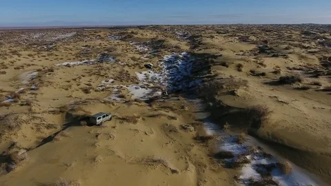 Aerial view of three suvs moving through the snow-covered desert in winter Stock Footage 80985363