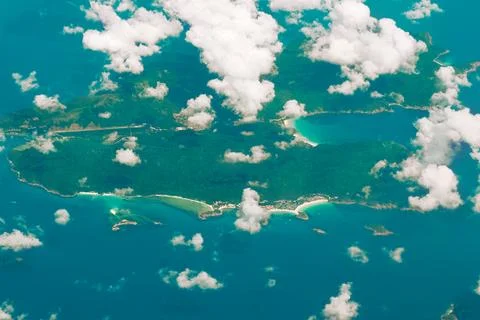 Aerial view through clouds to large island in the ocean. Stock Photos