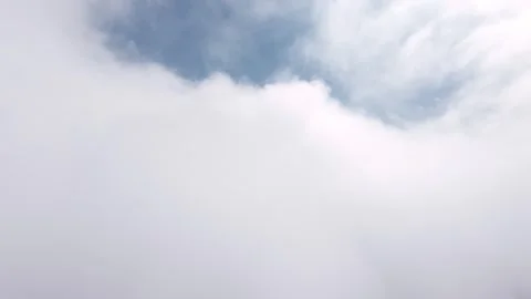 Aerial view through clouds revealing blue sky and distant landscape below Stock Footage 340411740