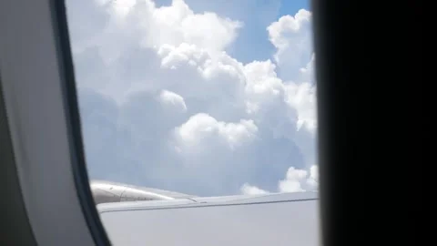 Aerial view through plane window with view of airplane wing over puffy whit.. Stock Footage 248962800