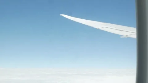 Aerial view through plane window with view of airplane wing over puffy whit.. Vídeos de archivo 329672232