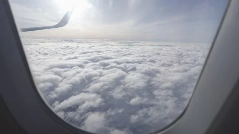 Aerial view through plane window with view of clouds and plane wing in sky .. Stock Footage 338331462