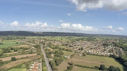 Aerial view, tilt down move. Traffic on roundabout, houses and fields in Tarv 스톡 동영상 95565179