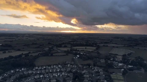 Aerial view, tilt up move. Dramatic fast moving sky and sunset over houses of Stock Footage 95563814