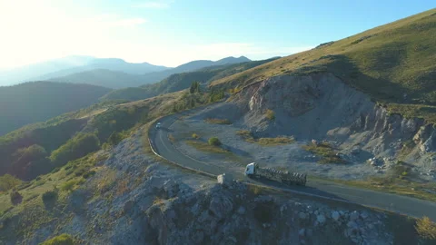 Aerial View Of Timber Lorry driving on winding mountain road in sunny day in Stock Footage 141647408