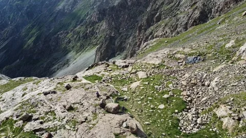 Aerial View of Tiny Hikers Trekking on Sunlit Mountain Slope Video stock 332221656