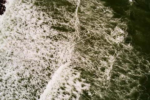 Aerial view Top down Waves crashing on sandy shore,Dark sea surface in summ.. Stock Photos