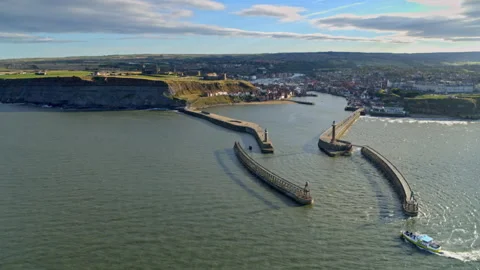 Aerial view of a tour boat entering Whitby Harbour Stock Footage 336803853