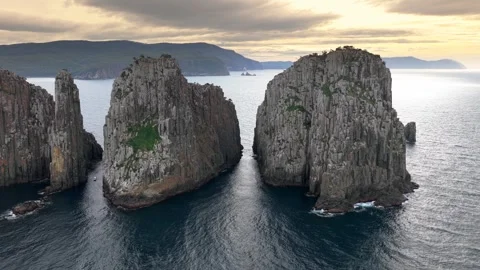 Aerial view of towering columnar rock cliffs beside a broad body of water Tasman Stockbeeldmateriaal 343705771