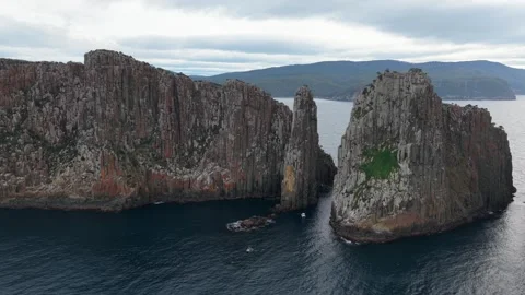 Aerial view of towering columnar rock cliffs beside a broad body of water Tasman 動画素材 343706216