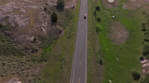 Aerial view tracking car down scenic mountain highway with lush green Stock Footage 286848773