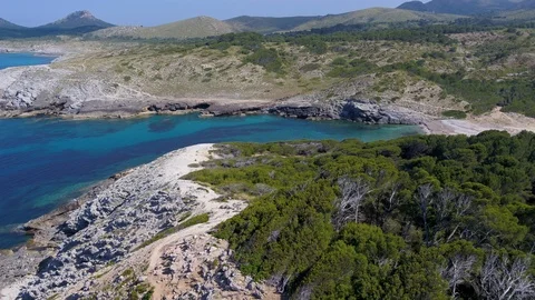 Aerial view tracking down dramatic coastline towards virgin turquoise beach Stock Footage 101566286