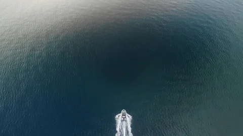 Aerial view tracking small boat speeding accross in calm blue ocean Stock Footage 113017547