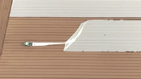 Aerial view of tractor applying row cover, United Kingdom. Stock Footage 332737380