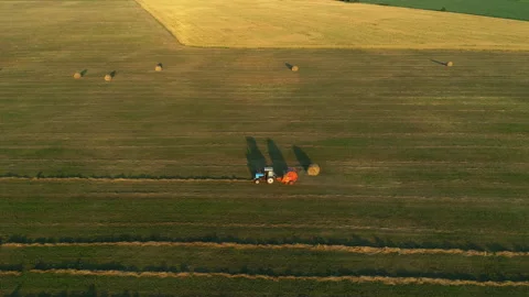 Aerial view tractor baling machine making silage bales on farmland, haystack Stock Footage 170129315