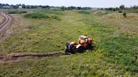 Aerial view of tractor with cable drum laying fiber optic hawser at countryside Stock Footage 300852541