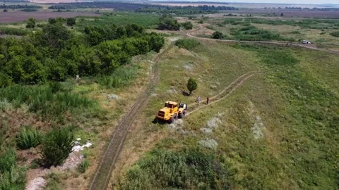 Aerial view of tractor with a cable drum laying fiber optic hawser Stock Footage 324819867