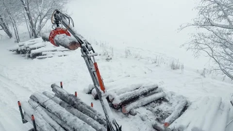 Aerial view tractor with a crane loads a trailer with logs in snow Stock Footage 169548405