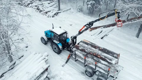 Aerial view tractor with a crane loads a trailer with logs. Drone shoot Stock Footage 169548672