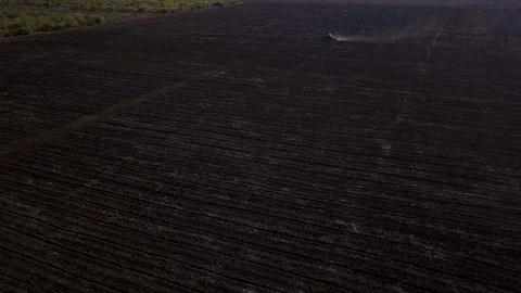 Aerial view of a tractor cultivating a fields with black soil for planting in 4K Stock Footage 81390853