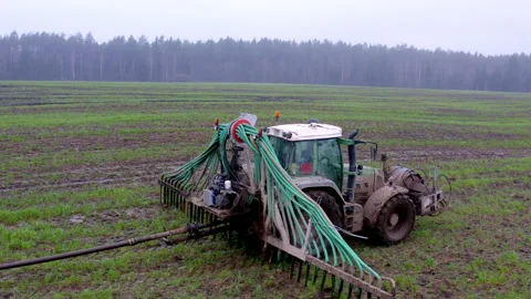 Aerial view. The tractor drives through the field and released l fertilizer. Video stock 220350588