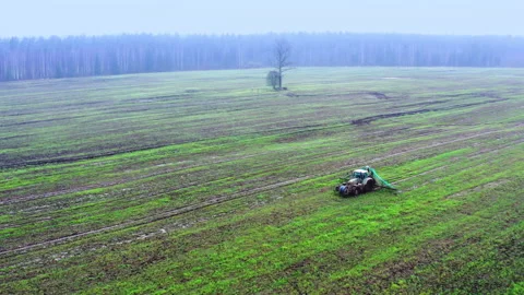 Aerial view. The tractor drives through the field and released fertilizer Stock Footage 225865864