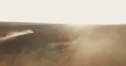Aerial view of tractor in the dust working in the field at sunset.  Vidéo 132105940