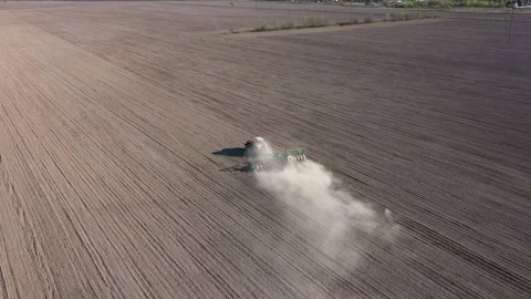 Aerial view of tractor with harrow system plowing ground on cultivated field Stock Footage 155328235