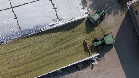 Aerial view of tractor loading grass silage into bunker silo, Italy. Stock Footage 344998095