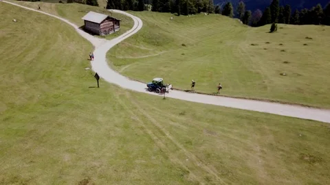 Aerial view of a tractor moving on a Dolomites Alpine road, sunny summer day Stock Footage 114355957