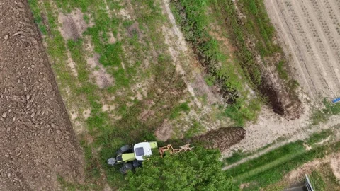 Aerial view of a tractor on a patchwork of green and plowed fields, slow motion Video stock 312413592