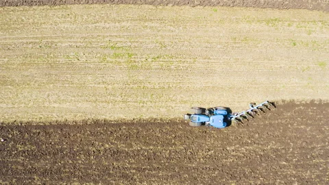 Aerial view of a tractor plowing the field on the farmland Stock Footage 136922018