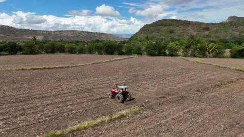 Aerial view of tractor plowing field, mountains in the background Stockbeeldmateriaal 333713532