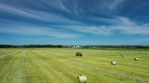 Aerial view of tractor uses trailed bale machine to collect straw in field and Stock Footage 170490197