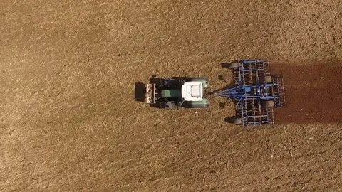Aerial view of a tractor at work on a agricultural fields - cultivating a field Stock Footage 74987702