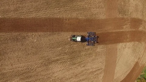 Aerial view of a tractor at work on a agricultural fields - cultivating a field Stock Footage 74987789