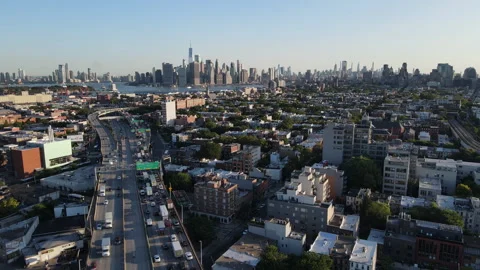Aerial view of traffic passing through Brooklyn with the NYC skyline behind Stock Footage 247205203