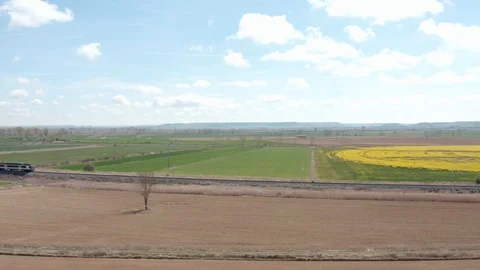 Aerial view of a train crossing farm fields in spring season Stock Footage 112242016