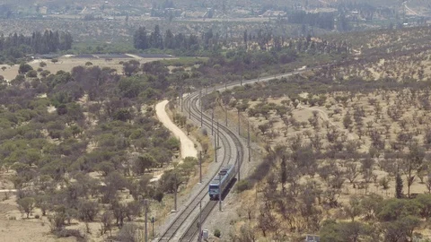 AERIAL VIEW OF TRAIN IN THE MIDDLE OF VALLEY WITH MOUNTAINS AND TREES AROUND IT Stock Footage 101244169