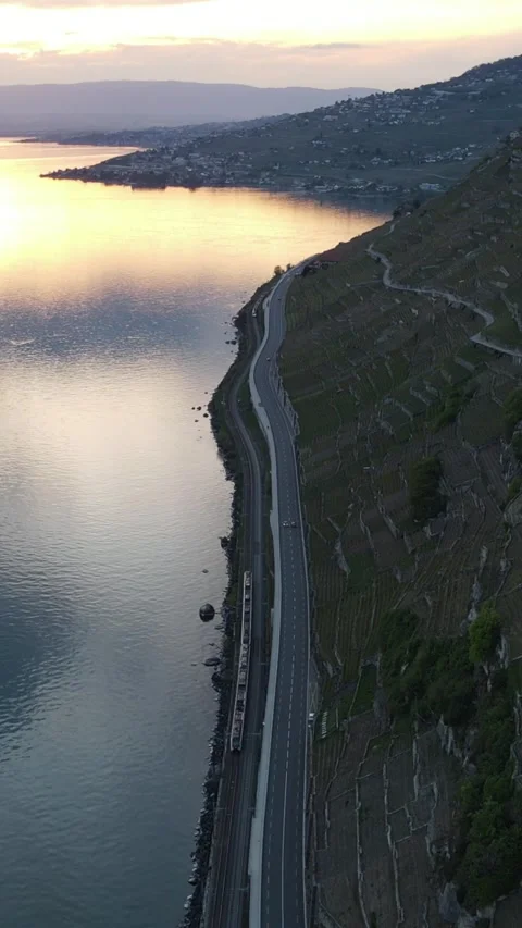 Aerial view of train moving along lakeside vineyard terraces at sunset Stockbeeldmateriaal 333030651