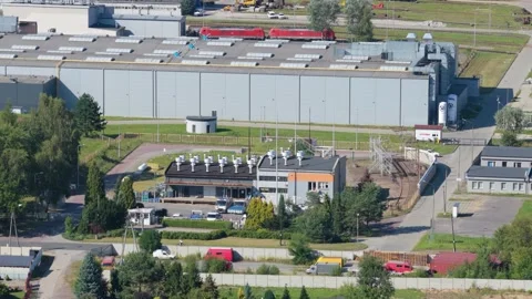 Aerial view of a train passing a large factory in an industrial zone 스톡 동영상 348267617