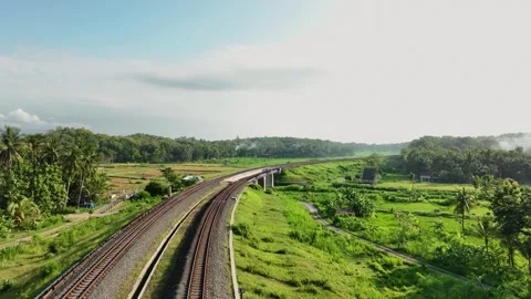 Aerial View of Train Passing Through a Lush Countryside Stock Footage 269748434